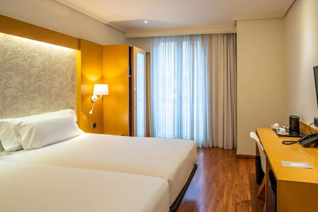 a hotel room with a large bed and a desk at Abba Rambla Hotel in Barcelona
