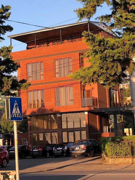 a red brick building with cars parked in front of it at Mzıurı House 1 in Batumi