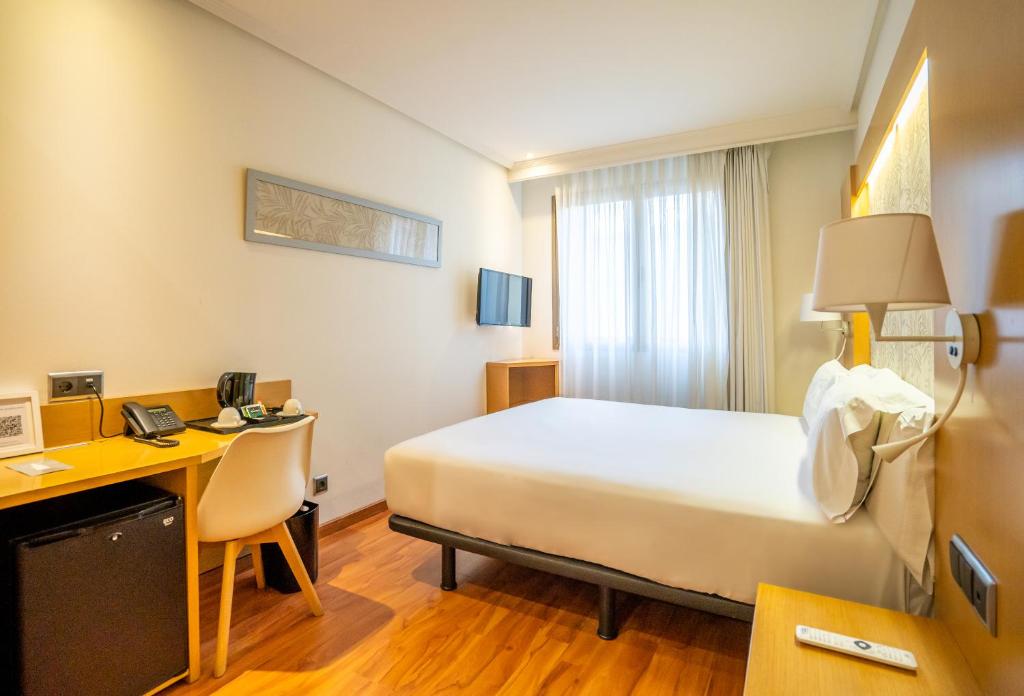 a hotel room with a bed and a desk with a computer at Abba Rambla Hotel in Barcelona