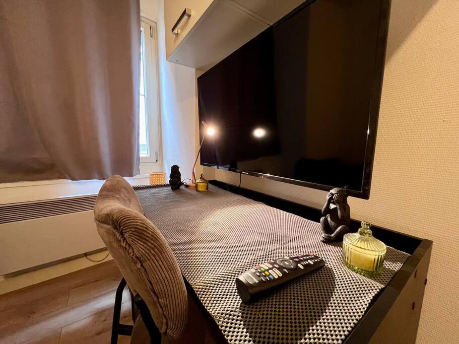 - un salon avec une télévision et une table avec télécommande dans l'établissement Studio 1 personne Au pied de la Citadelle, à Besançon