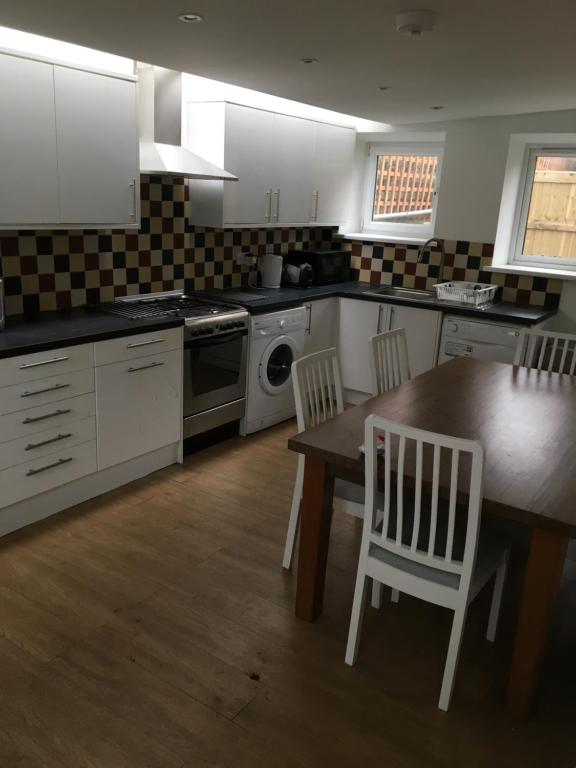 a kitchen with white cabinets and a table and chairs at Spacious duplex flat in London