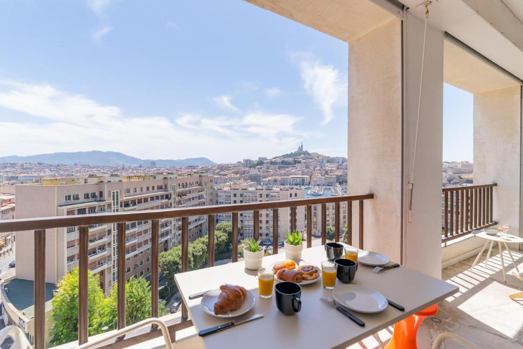 une table sur un balcon avec vue sur une ville dans l'établissement Le Skyline - Apt climatisé avec terrasse Marseille, à Marseille