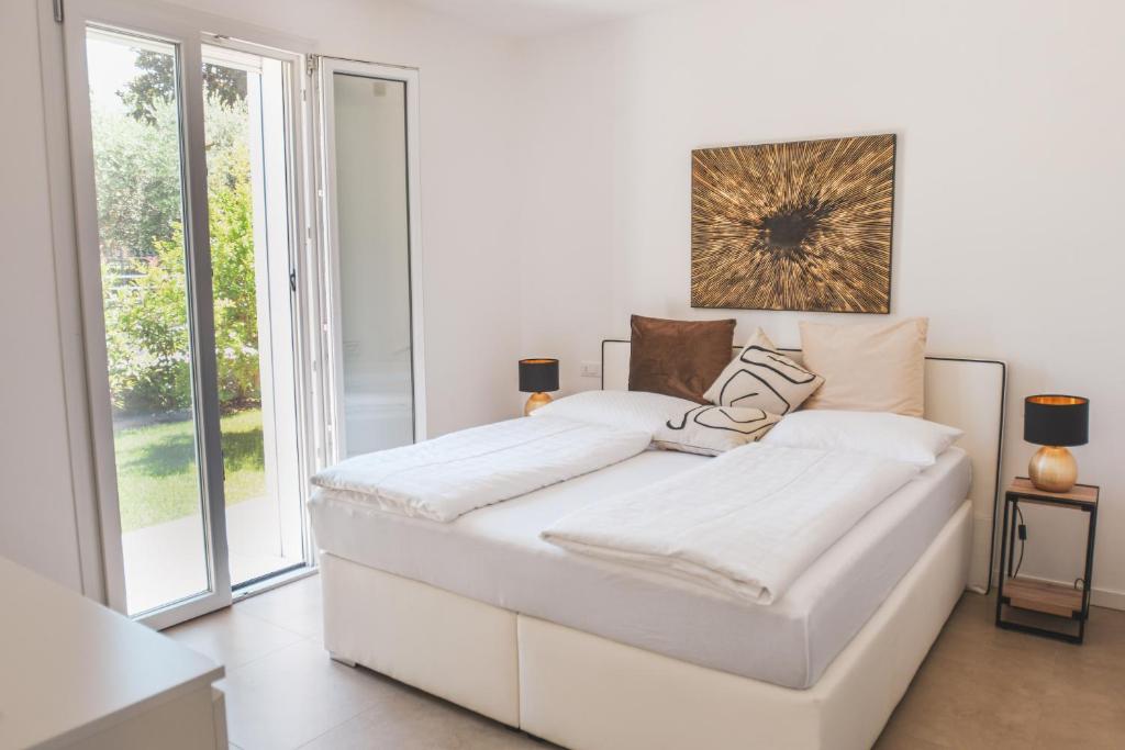 un lit blanc dans une chambre avec une grande fenêtre dans l'établissement Villa My Lagozise, à Pacengo di Lazise 29 autres photos