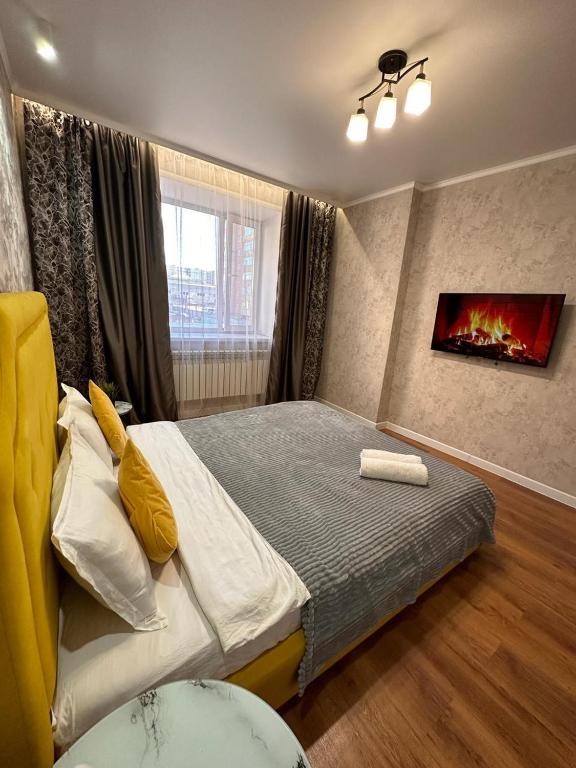 a bedroom with a large bed with a fireplace at ЖК Абай 1 in Kokshetau