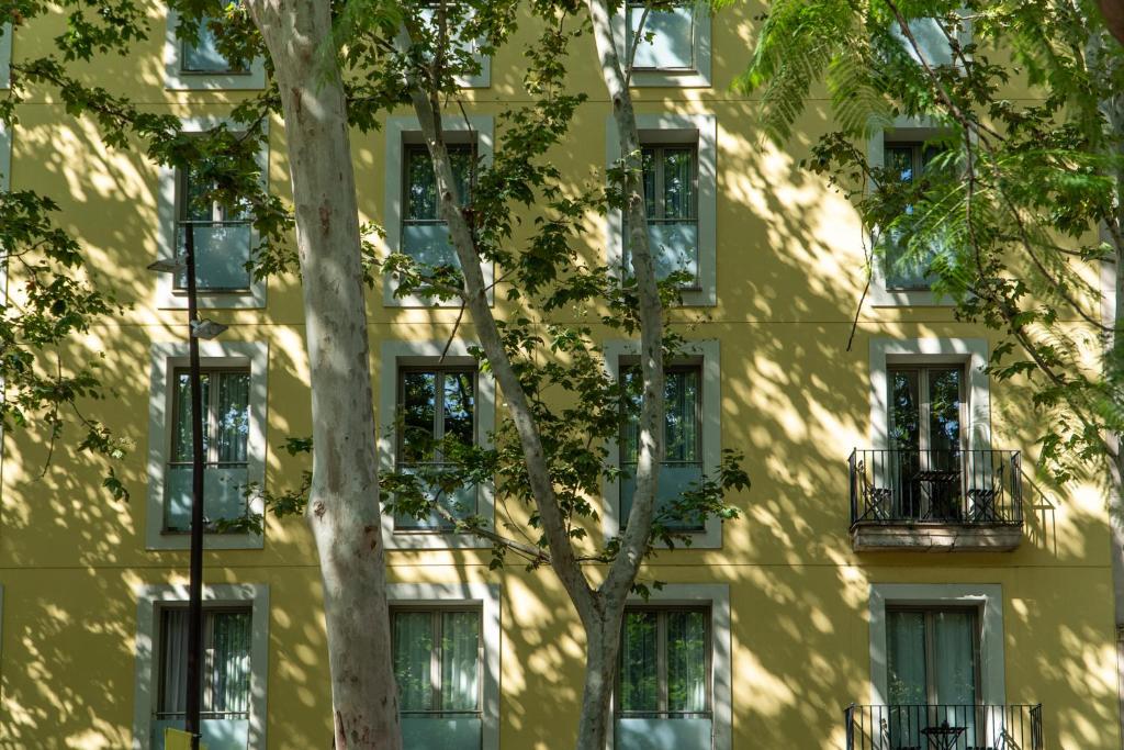 a yellow building with trees in front of it at Abba Rambla Hotel in Barcelona