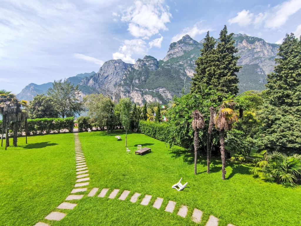 a green park with mountains in the background at Apartment Am See by Interhome in Riva del Garda