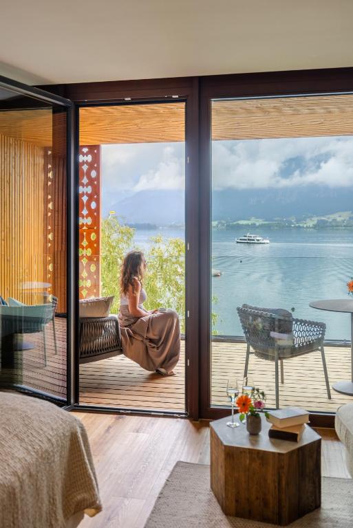 a woman sitting on a chair in front of a window at Hotel Seevilla Wolfgangsee in St. Wolfgang