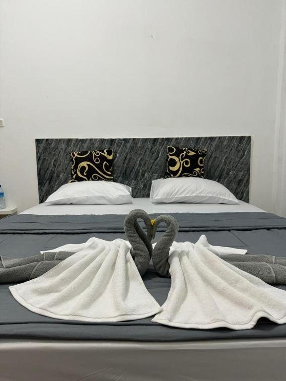 two beds with towels and swans laying on them at Black Sweet Homestay Dua in Gili Islands