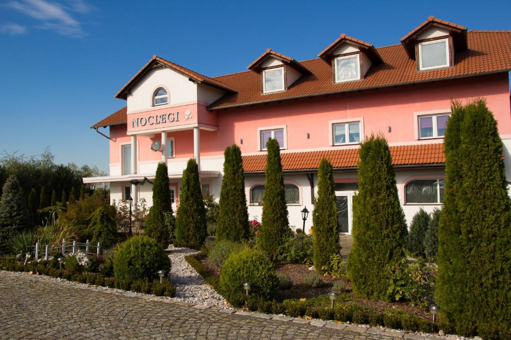 un grand bâtiment rose avec des arbres devant lui dans l'établissement Noclegi Biała Róża, à Bolesławiec
