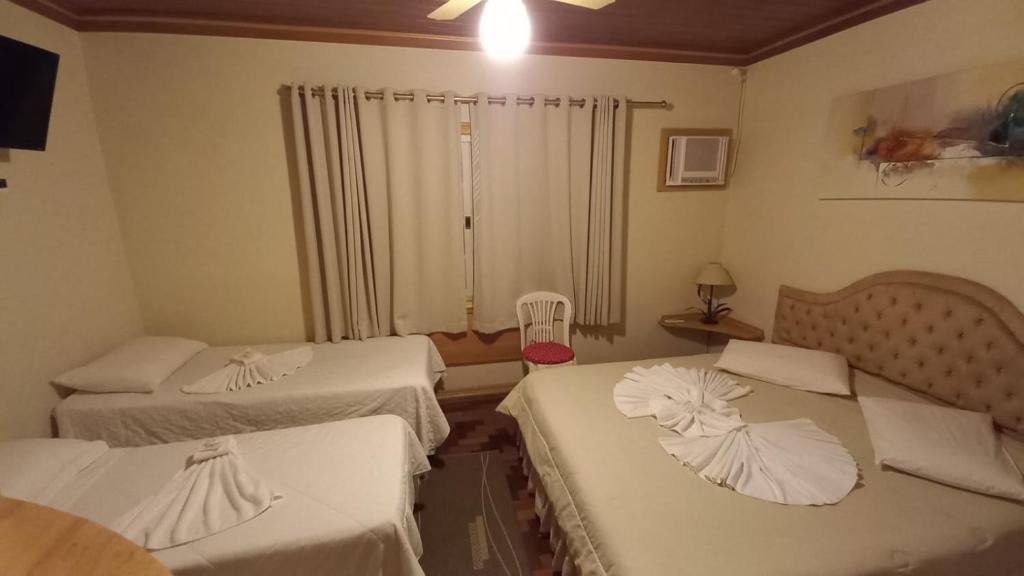 a hotel room with two beds and a window at Pousada Eco Da Montanha in Passa Quatro