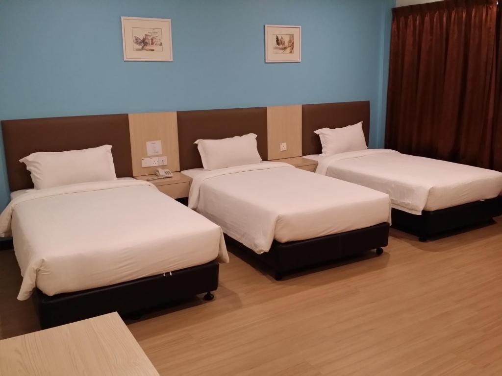 a room with three beds with white sheets at MJ Hotel in Sibuga