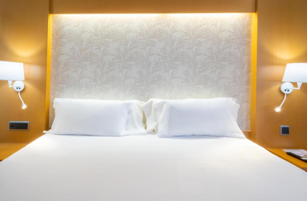 a bedroom with a white bed with two pillows at Abba Rambla Hotel in Barcelona