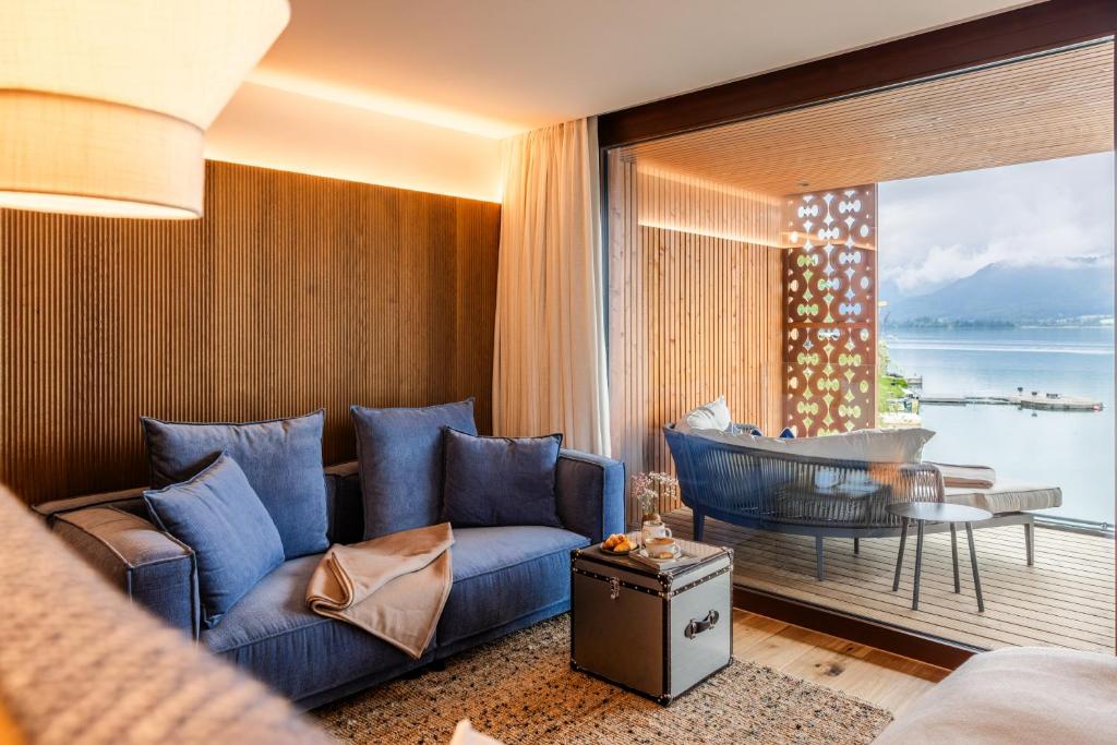 a living room with a blue couch and a large window at Hotel Seevilla Wolfgangsee in St. Wolfgang