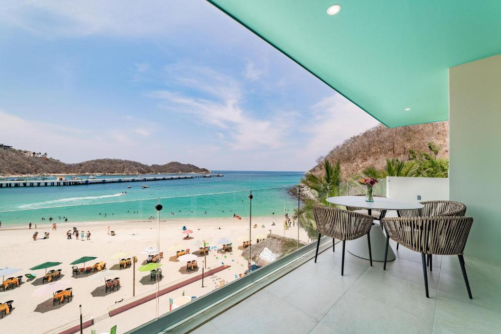 une vue sur une plage depuis une pièce avec une table et des chaises dans l'établissement 3044 - Playa Sur Santa Cruz 301, à Santa Cruz Huatulco