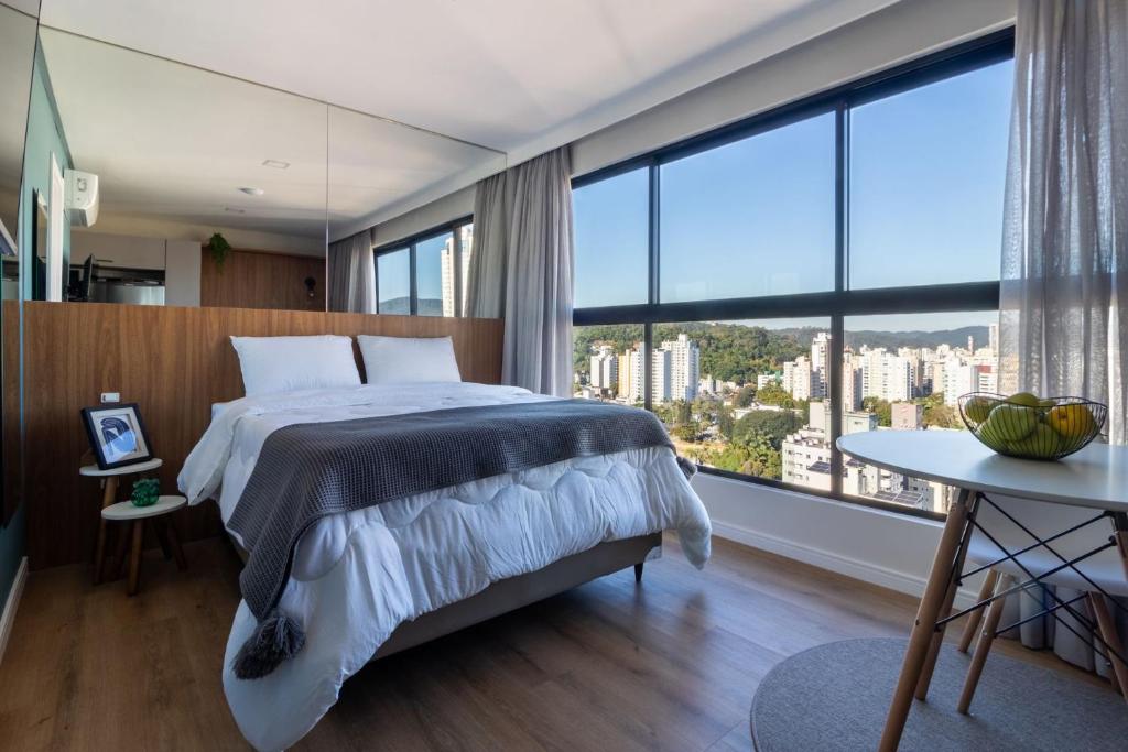 Un dormitorio con una cama grande y una ventana grande. en Loft próximo a Vila Germânica e FURB com vaga., en Blumenau