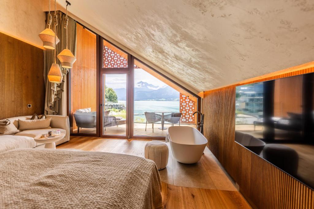 a bedroom with a tub and a view of the ocean at Hotel Seevilla Wolfgangsee in St. Wolfgang