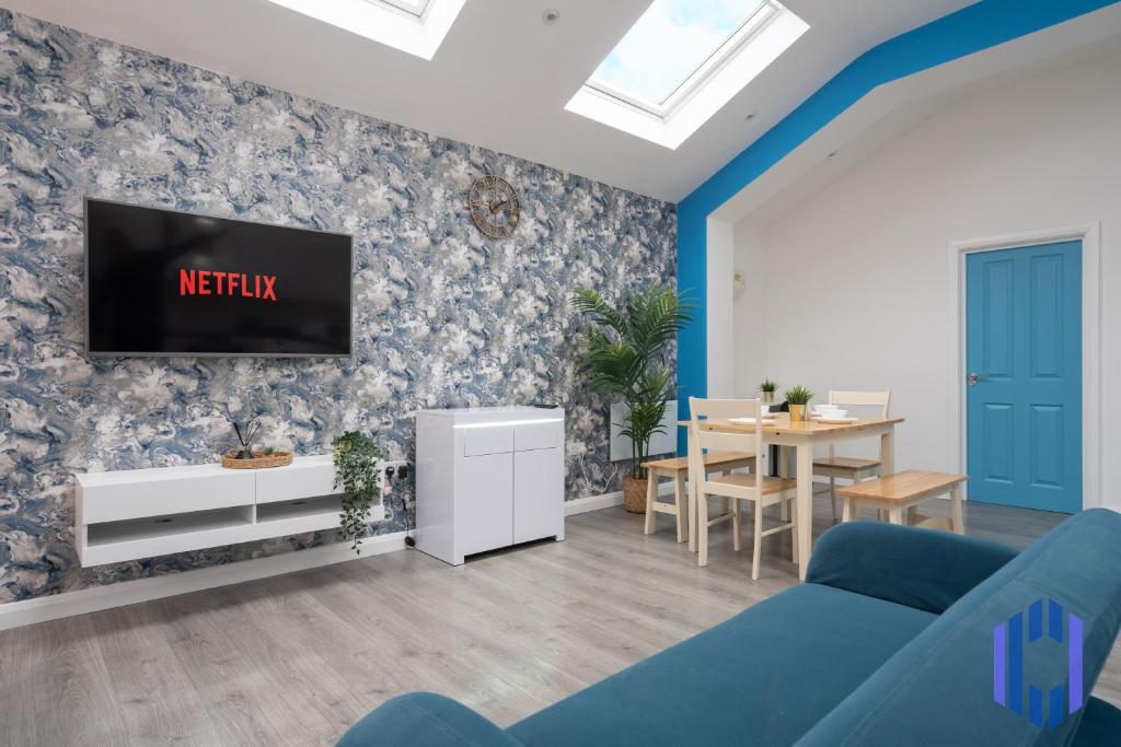 a living room with a tv on a wall at Santorini Blues by CEFAS - Free Parking - Bungalow - Near Airport in Manchester