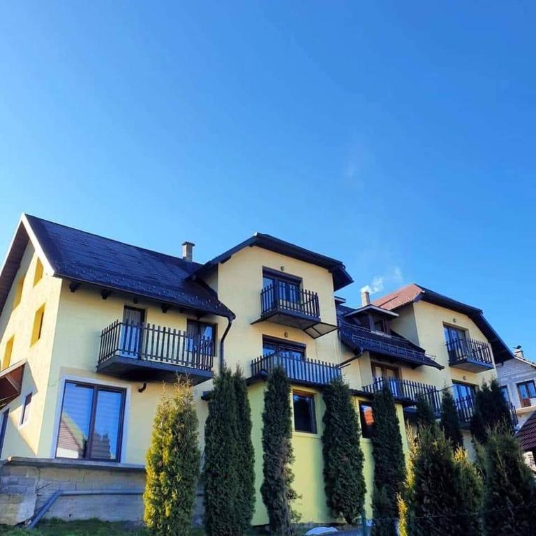 a large yellow building with balconies and trees at Apartman Jevtic Zlatibor in Zlatibor