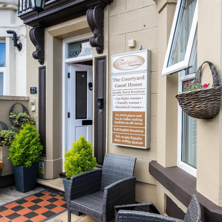 a front door of a guest house with chairs and a sign at The Courtyard Guest House in Great Yarmouth