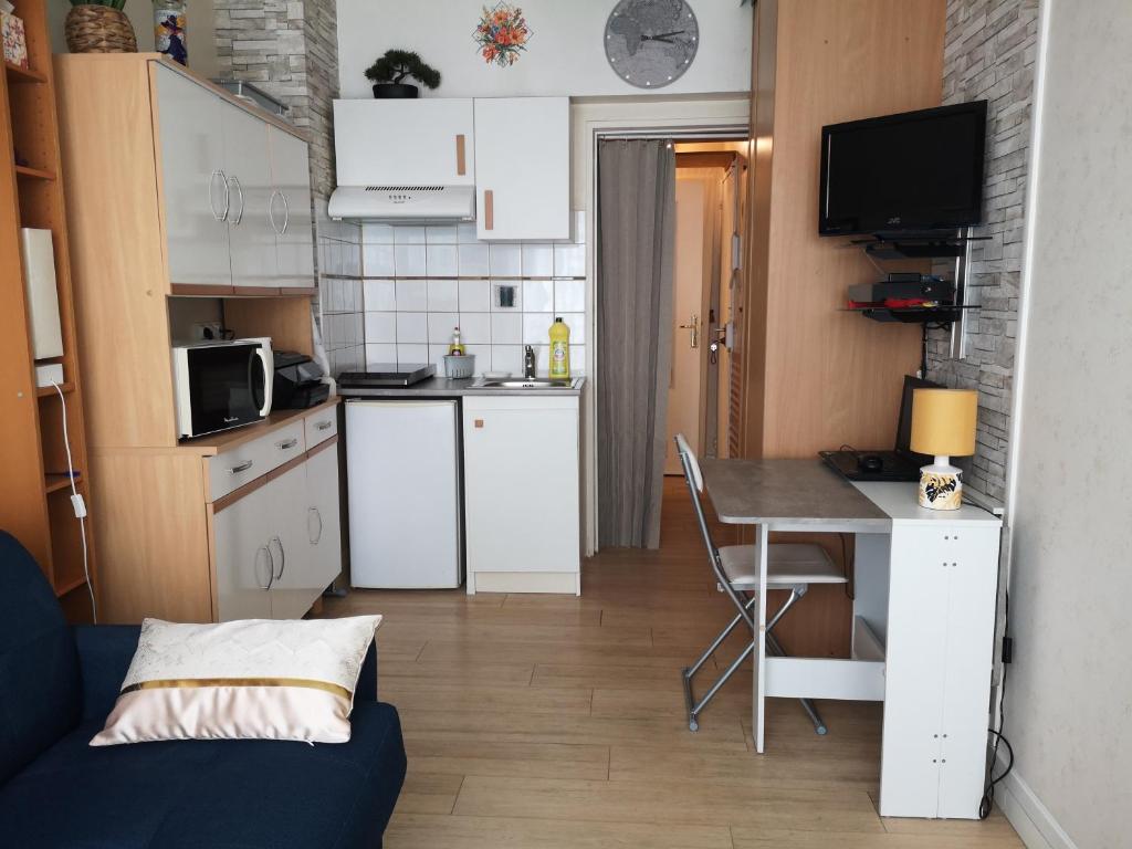 une petite cuisine avec un bureau et une table avec un canapé dans l'établissement Studette meublée, Ranelagh Paris 16e, à Paris