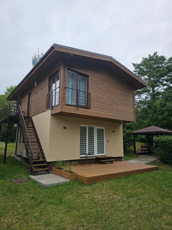 een groot huis met een veranda en een trap bij Apartmens LORETA in Šventoji