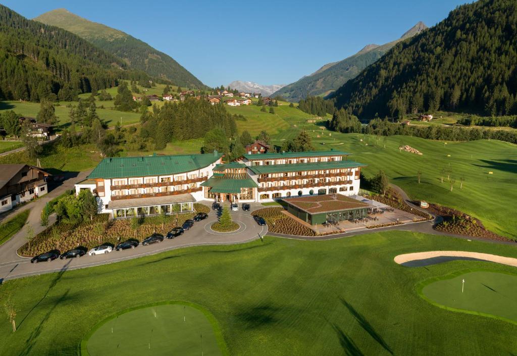 z powietrza widok na hotel i pole golfowe w obiekcie Defereggental Hotel & Resort w mieście Sankt Veit in Defereggen