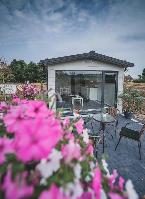 a patio with a table and chairs and pink flowers at Lawendowy Zakątek 3 domek z balią in Sominy