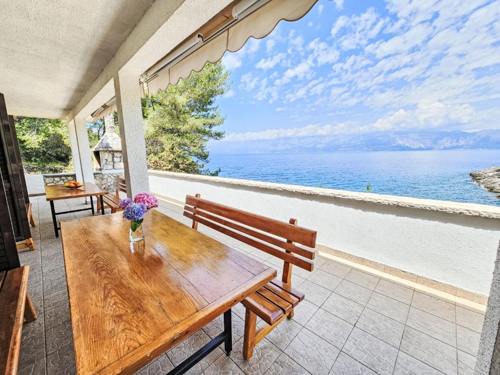 een houten bank op een patio met uitzicht op de oceaan bij Apartment Octopus-5 by Interhome in Bogomolje