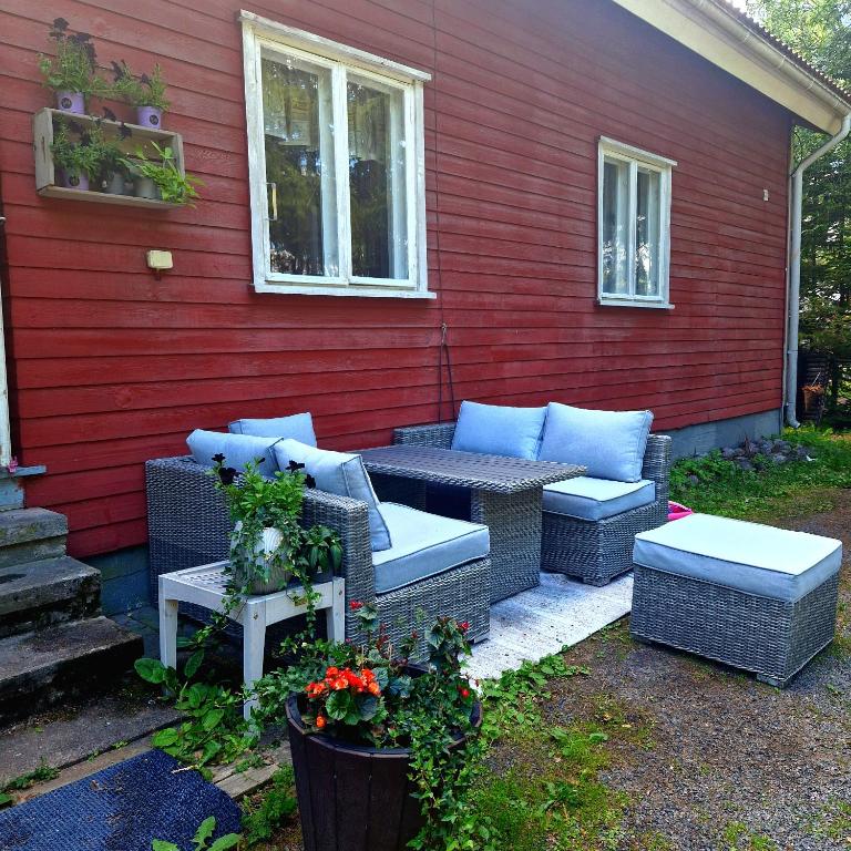 a patio with wicker furniture next to a red wall at Majoitus Eura in Kauttua