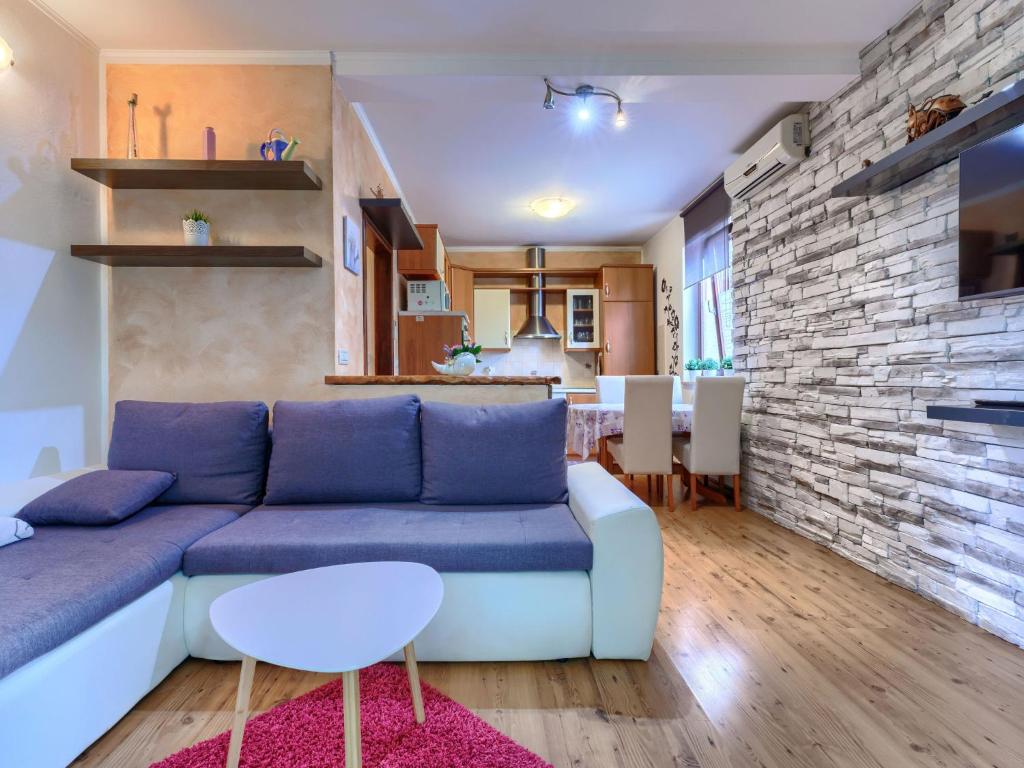 Una sala de estar con un sofá azul y una pared de ladrillos. en Apartment Apartmani Amaii-1 by Interhome, en Karigador