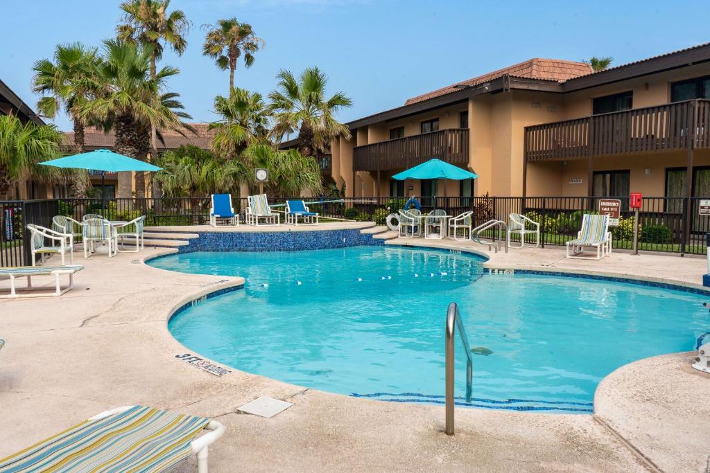 サウス・パドレ・アイランドにあるPelicans Perch Charming 1BR Near Beach with Patio 160の- リゾート内のスイミングプール(椅子、パラソル付)