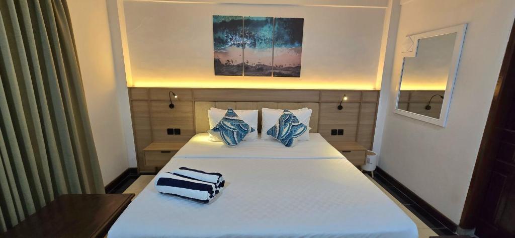 Un dormitorio con una cama blanca con almohadas azules. en C&C Jayakarta Apartment Legian Kuta Bali, en Seminyak