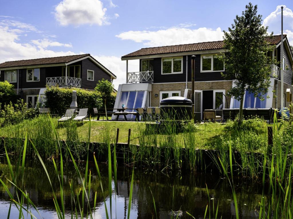a house with a lake in front of it at Holiday Home Ellersinghuis by Interhome in Vlagtwedde