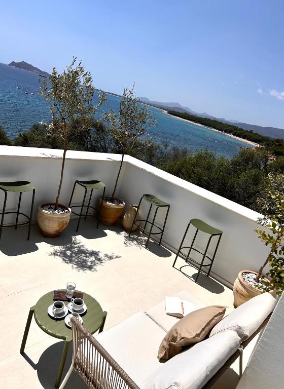 a patio with a couch and tables and the ocean at Vireo Rooms in Santa Maria Navarrese