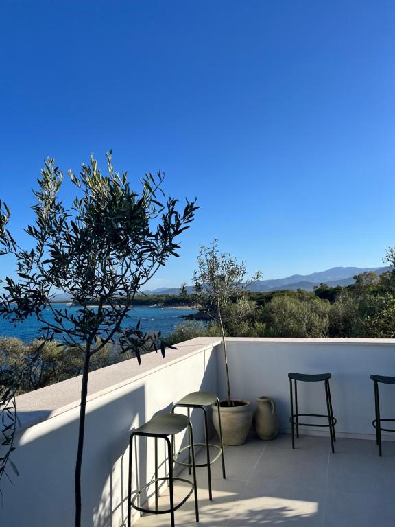 a group of chairs and a tree on a balcony at Vireo Rooms in Santa Maria Navarrese
