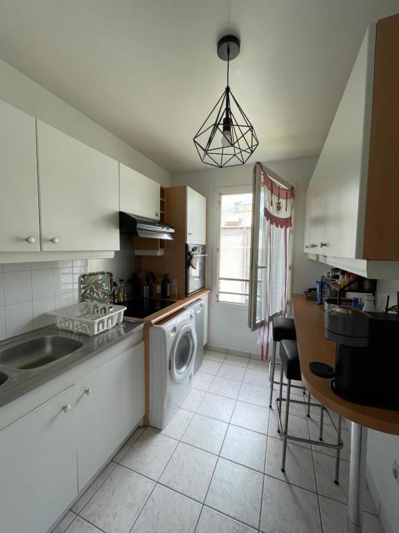 une cuisine avec un évier et une machine à laver dans l'établissement Appartement avec vue sur le Stade de France & le canal, à Saint-Denis