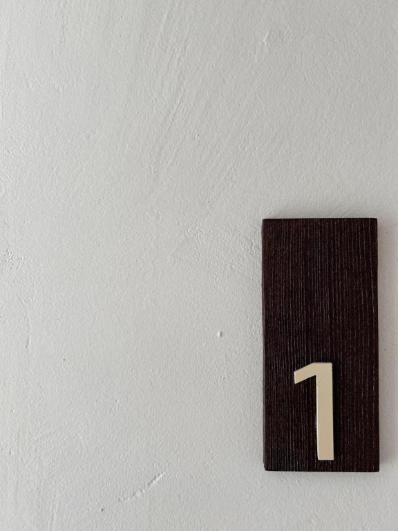 a black plaque with the number one on a wall at Vireo Rooms in Santa Maria Navarrese