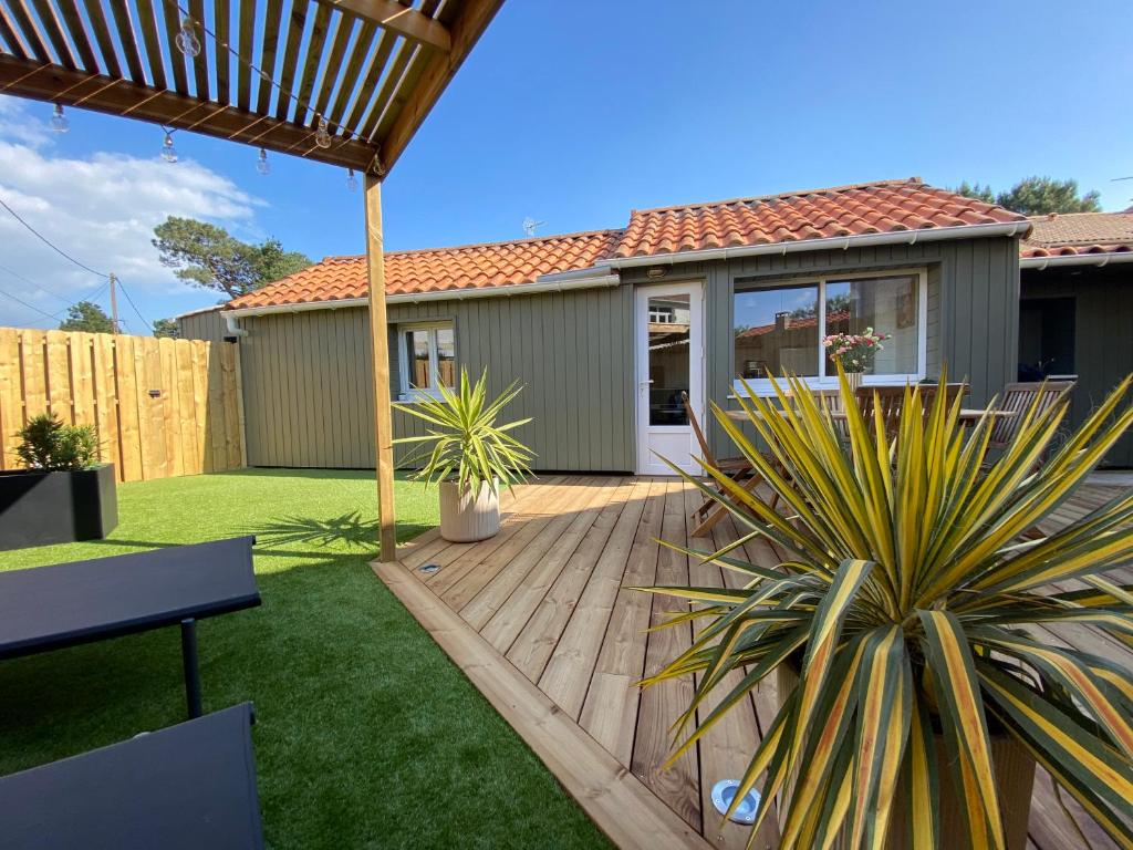 un jardin avec une terrasse en bois et une maison dans l'établissement Margottine, confortable cocon au calme, à Saint-Brévin-les-Pins