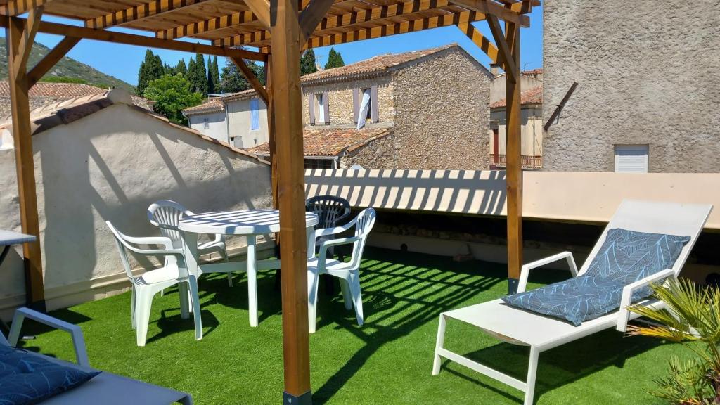 patio ze stołem i krzesłami na trawie w obiekcie La Forgeolie w mieście Causses-et-Veyran