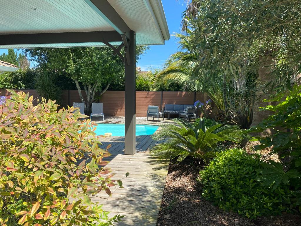 une cour avec une piscine et une pergola dans l'établissement Villa proche du bassin -piscine, à Gujan-Mestras