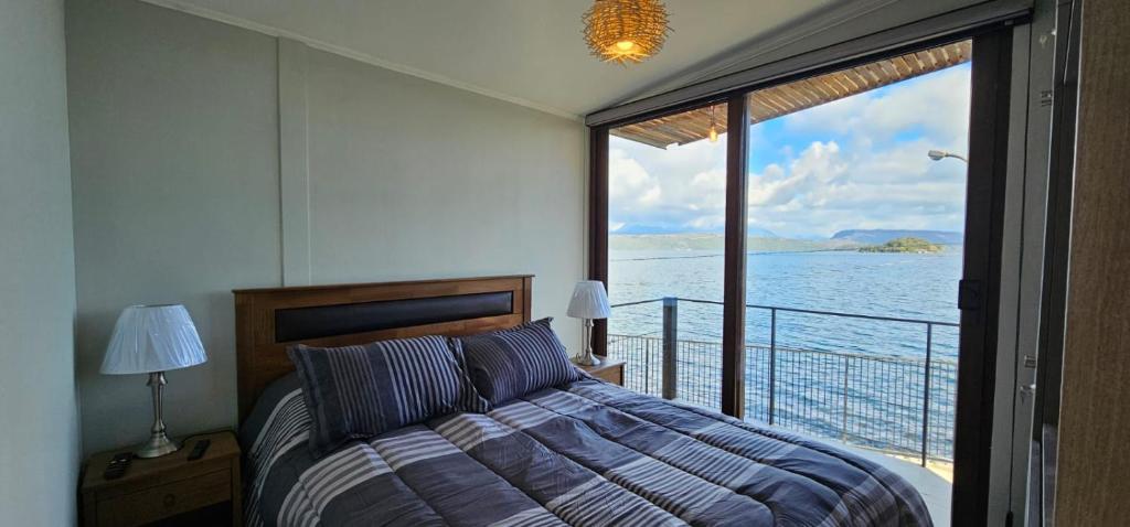 a bedroom with a bed and a view of the water at Cabaña 1 Lican Ray primera linea in Licán Ray