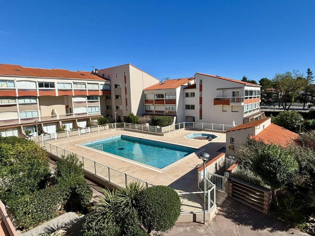 un complexe d'appartements avec une piscine et deux bâtiments dans l'établissement Studio cabine 4 couchages ARGELES SUR MER AR580-258, à Argelès-sur-Mer