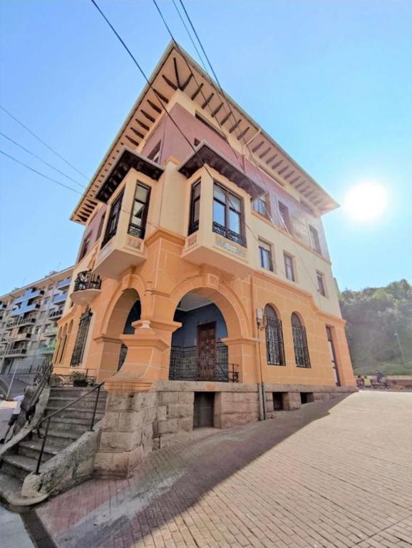 a yellow building with an archway on top of it at Soul Etxia in Bermeo