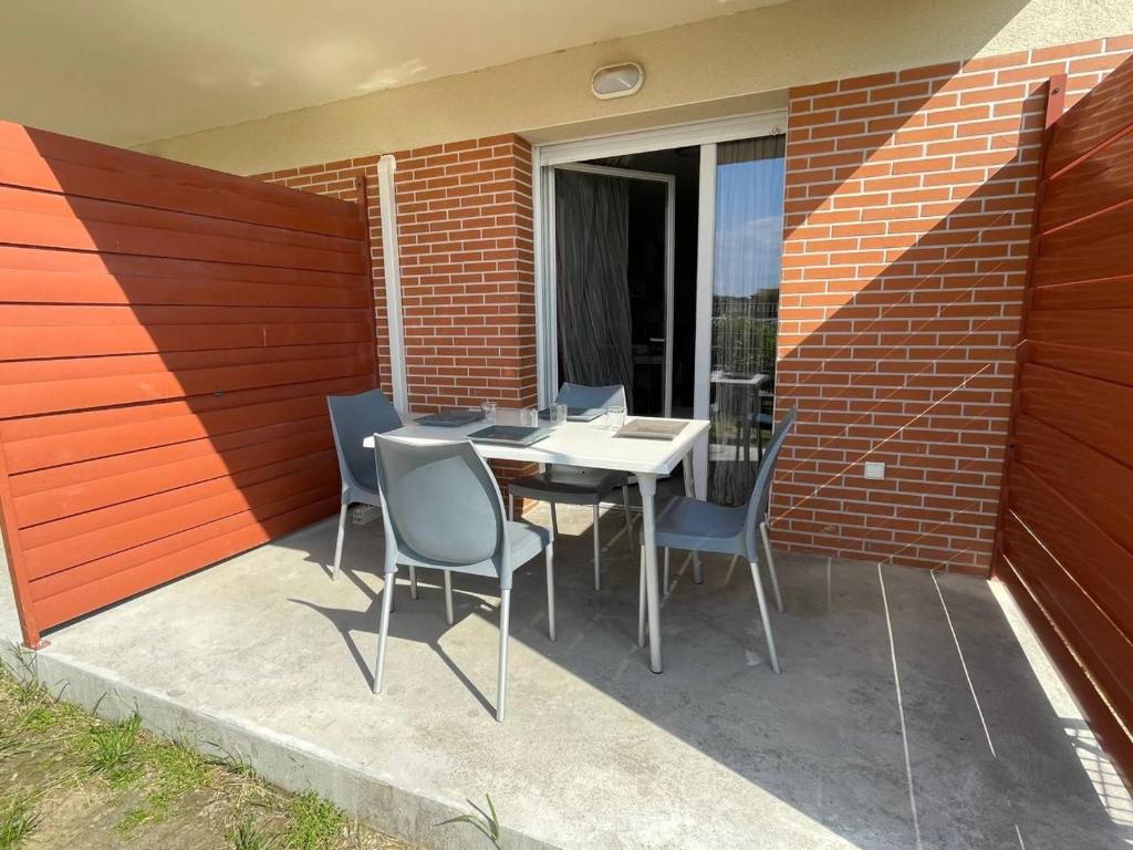 un patio avec une table et des chaises et un mur de briques dans l'établissement Argelès sur mer - Appartement deux pièces - AR920-006, à Argelès-sur-Mer