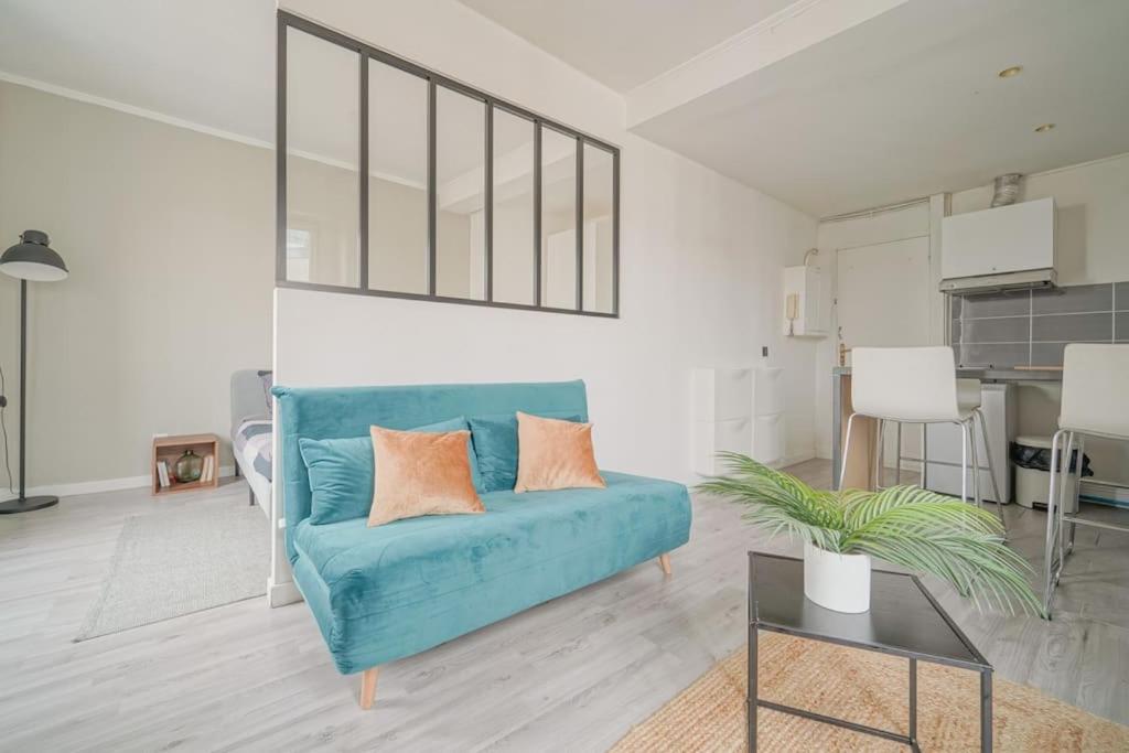 un salon avec un canapé bleu et une table dans l'établissement Doorman - NEW Audonien Modern 1BR Quick to Paris, à Saint-Ouen