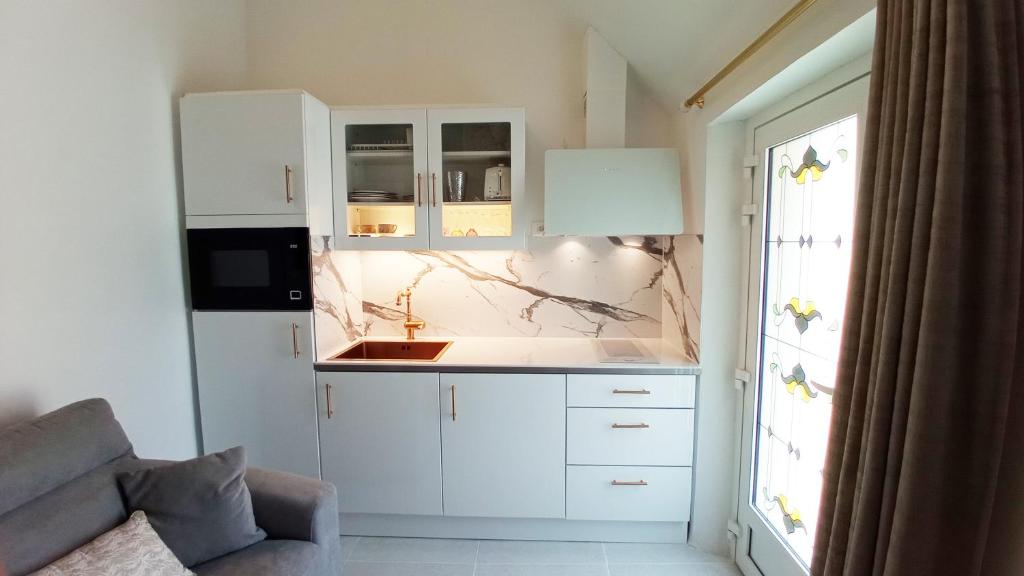 Una cocina con gabinetes blancos y un fregadero. en D-DAY's, en Bayeux