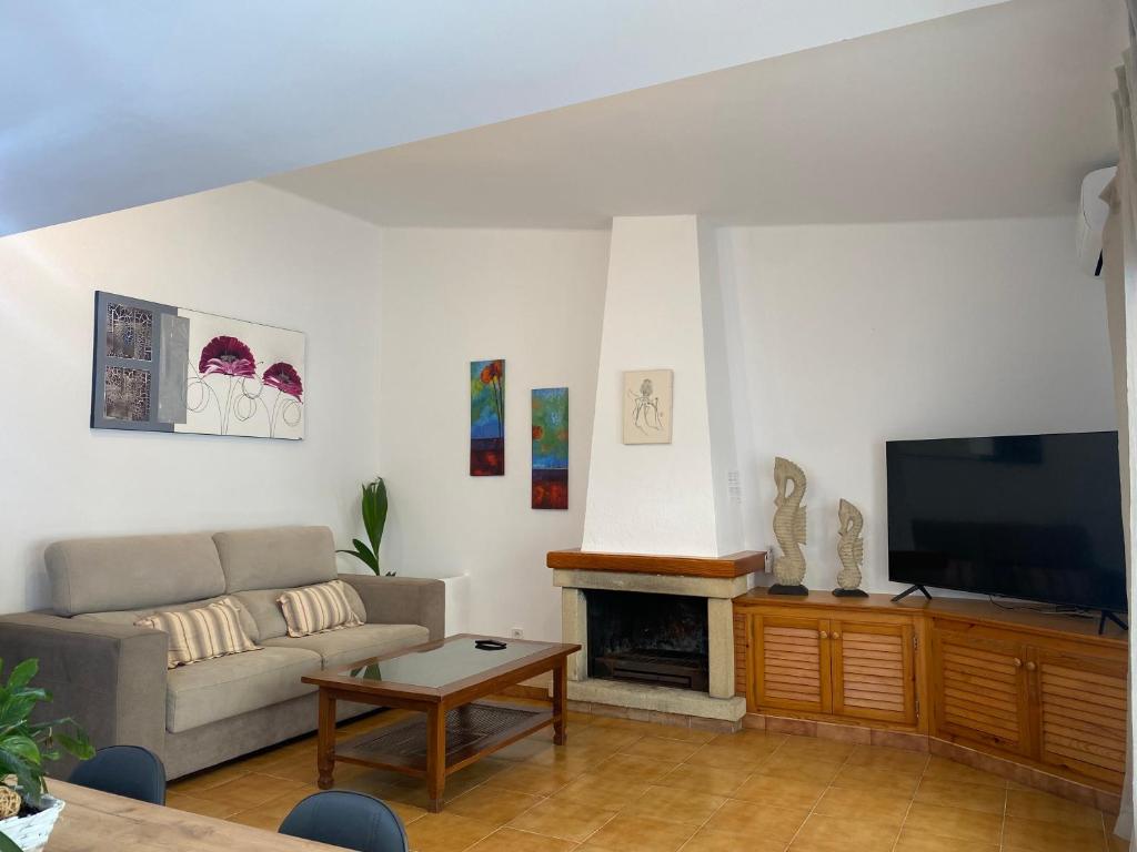 a living room with a couch and a flat screen tv at Casa con terraza, piscina y zona barbacoa in Montrás