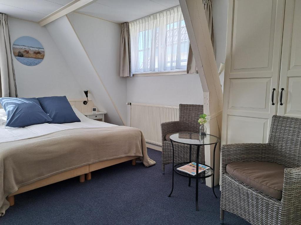 - une chambre avec un lit, deux chaises et une fenêtre dans l'établissement Hotel Het Gouden Boltje, à De Koog