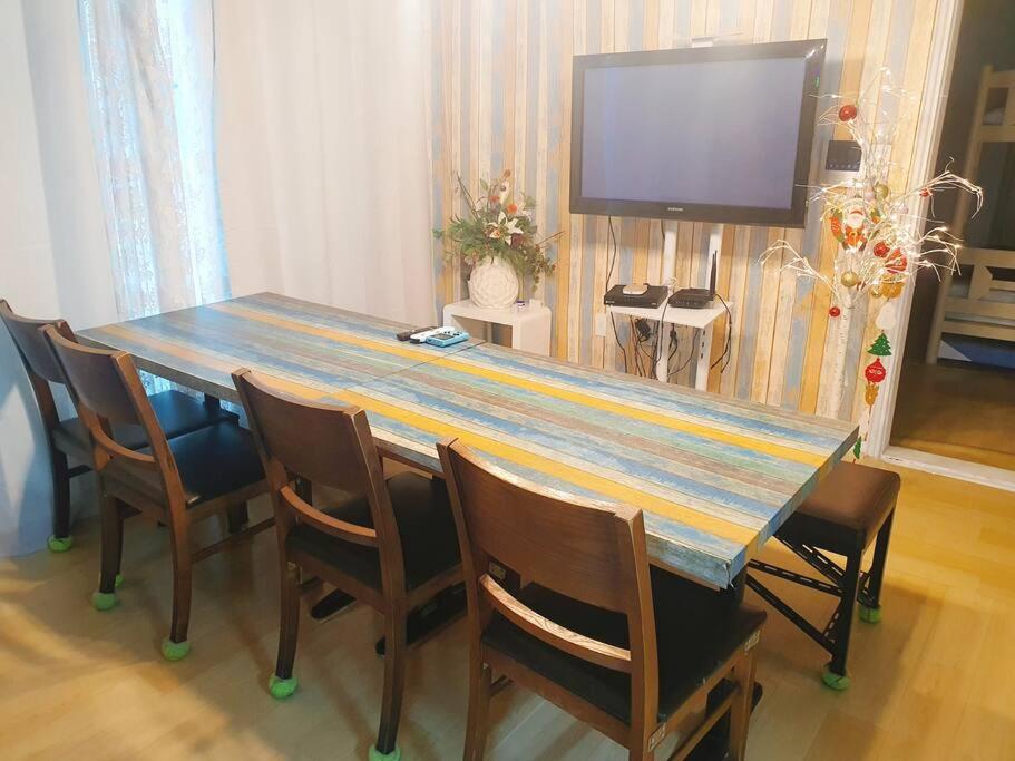 a wooden table with chairs and a television in a room at Light house hongdae Open sale in Seoul