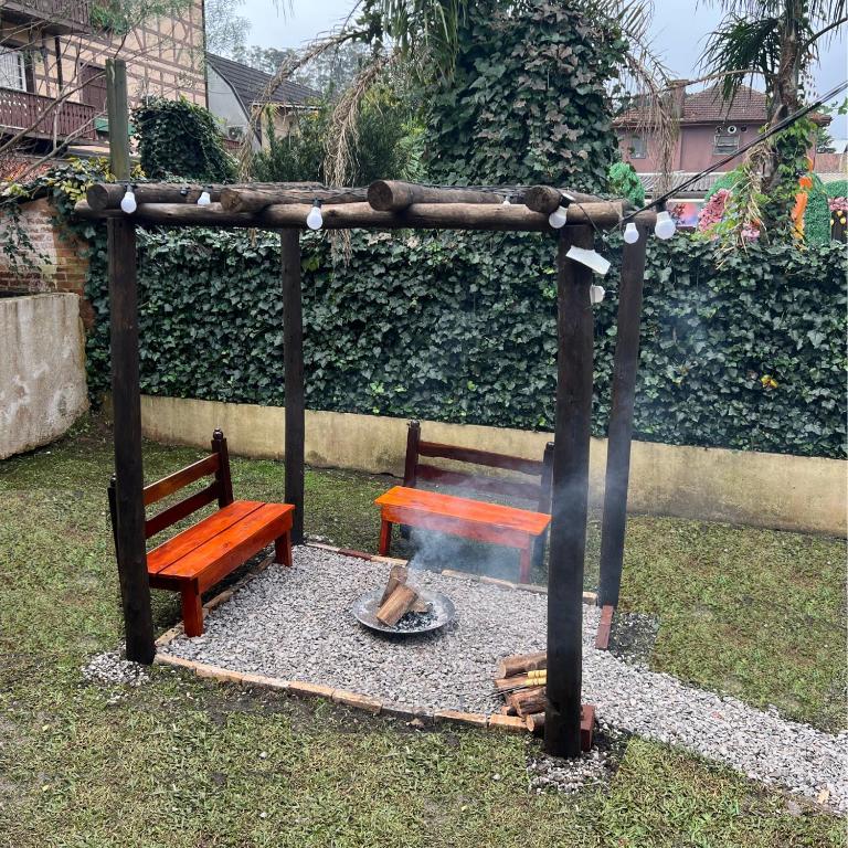 a fire pit with a bench and a table at Casa mais Central de Gramado in Gramado